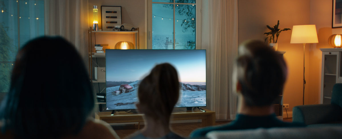 Een gezin in een woonkamer, kijkend naar een groot televisiescherm