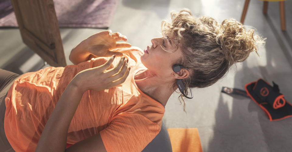 Atleet gebruikt open-ear koptelefoon tijdens een binnen workout