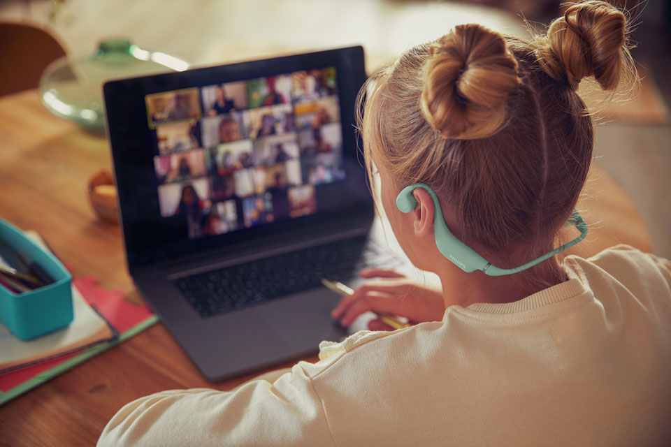 Een meisje dat comfortabele koptelefoon voor kinderen gebruikt voor een schoolactiviteit.