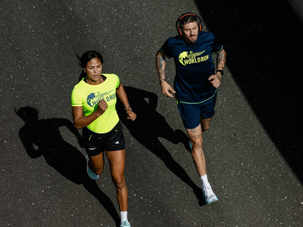 Twee hardlopers doen hun best om de auto voor te blijven.