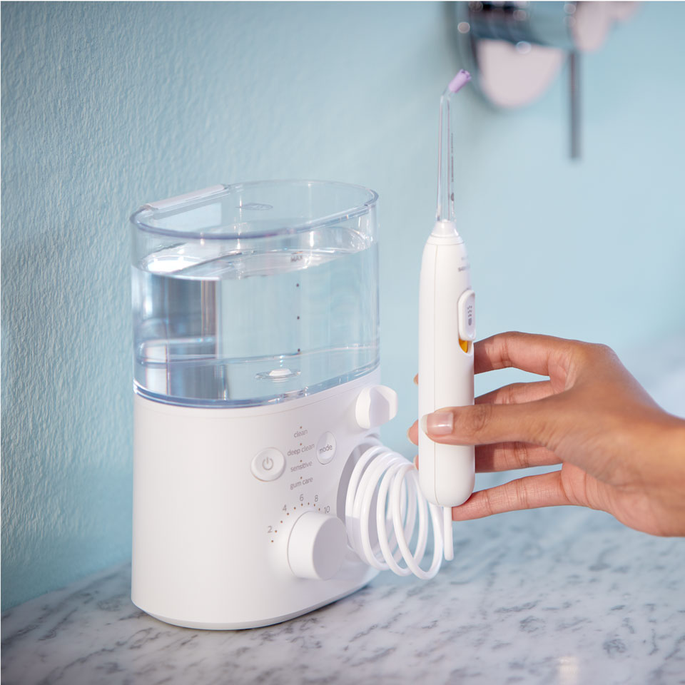 Hand die naar een Power Flosser op een werkblad reikt